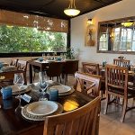 Interior Gastrobar Urban Mô di Mahón dengan suasana hangat dan stylish, menampilkan meja kayu, pencahayaan lembut, serta dekorasi elegan, ideal untuk menikmati hidangan lokal dan internasional yang inovatif