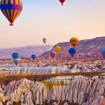 Balon udara warna-warni terbang di atas lanskap unik Cappadocia, Turki