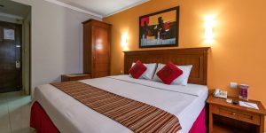 Kamar hotel bintang 2 yang sederhana namun nyaman, dengan tempat tidur double, pencahayaan hangat, dan fasilitas dasar seperti telepon serta meja kecil