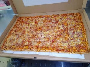 Pizza jumbo dengan topping keju melimpah dan potongan daging