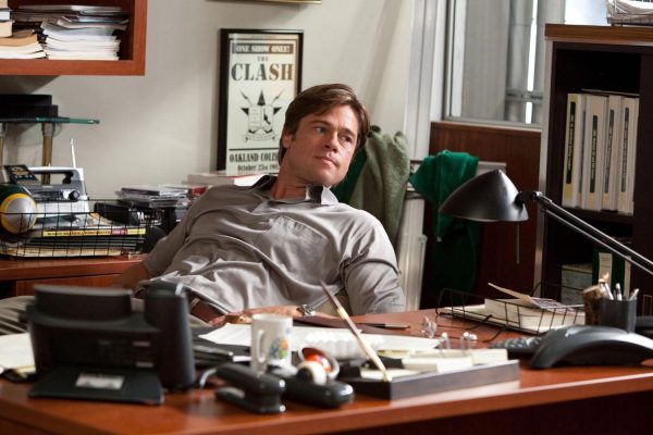 Belajar Strategi Manajemen dari Film-Film Bisnis Populer Adegan Brad Pitt sebagai Billy Beane dalam film Moneyball di ruang kerjanya